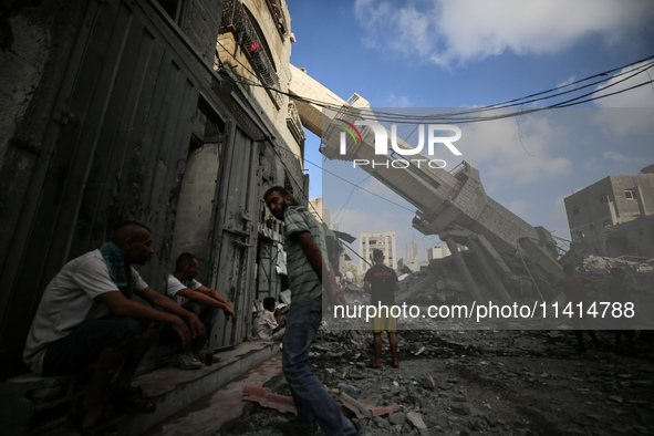 Palestinians are standing on the rubble of Abdullah Azzam Mosque, destroyed in Israeli bombardment in Nuseirat, central Gaza Strip, on July...