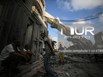 Palestinians are standing on the rubble of Abdullah Azzam Mosque, destroyed in Israeli bombardment in Nuseirat, central Gaza Strip, on July...