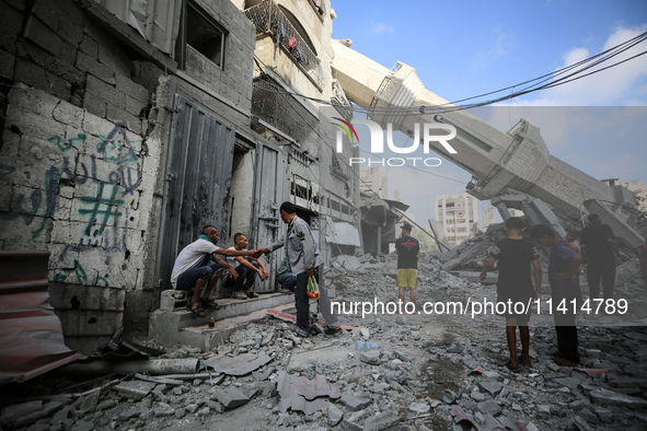 Palestinians are standing on the rubble of Abdullah Azzam Mosque, destroyed in Israeli bombardment in Nuseirat, central Gaza Strip, on July...