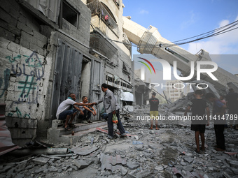 Palestinians are standing on the rubble of Abdullah Azzam Mosque, destroyed in Israeli bombardment in Nuseirat, central Gaza Strip, on July...