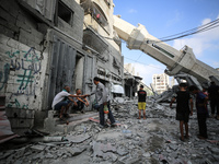 Palestinians are standing on the rubble of Abdullah Azzam Mosque, destroyed in Israeli bombardment in Nuseirat, central Gaza Strip, on July...