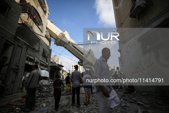 Palestinians are standing on the rubble of Abdullah Azzam Mosque, destroyed in Israeli bombardment in Nuseirat, central Gaza Strip, on July...