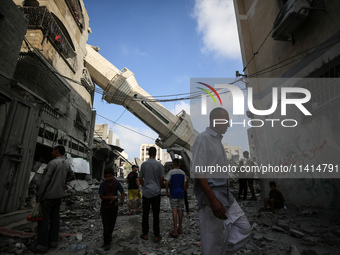 Palestinians are standing on the rubble of Abdullah Azzam Mosque, destroyed in Israeli bombardment in Nuseirat, central Gaza Strip, on July...