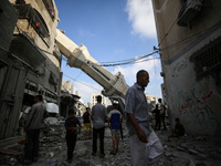 Palestinians are standing on the rubble of Abdullah Azzam Mosque, destroyed in Israeli bombardment in Nuseirat, central Gaza Strip, on July...