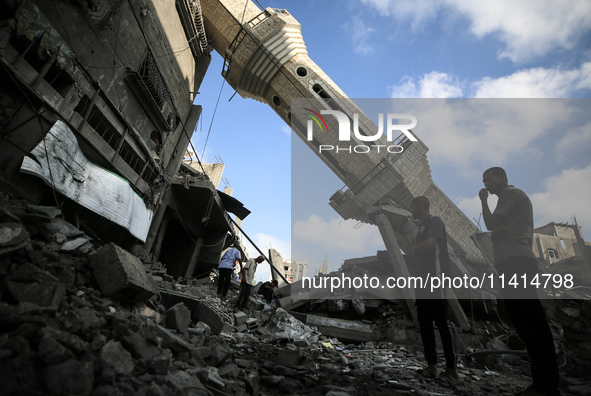 Palestinians are standing on the rubble of Abdullah Azzam Mosque, destroyed in Israeli bombardment in Nuseirat, central Gaza Strip, on July...