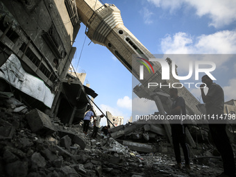 Palestinians are standing on the rubble of Abdullah Azzam Mosque, destroyed in Israeli bombardment in Nuseirat, central Gaza Strip, on July...