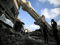 Palestinians are standing on the rubble of Abdullah Azzam Mosque, destroyed in Israeli bombardment in Nuseirat, central Gaza Strip, on July...