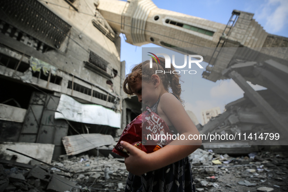 A Palestinian girl is walking in front of Abdullah Azzam Mosque, destroyed in Israeli bombardment, in Nuseirat, central Gaza Strip, on July...