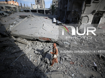 Palestinians are standing on the rubble of Abdullah Azzam Mosque, destroyed in Israeli bombardment in Nuseirat, central Gaza Strip, on July...