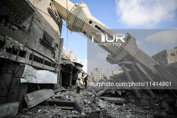 Palestinians are standing on the rubble of Abdullah Azzam Mosque, destroyed in Israeli bombardment in Nuseirat, central Gaza Strip, on July...