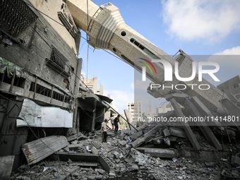 Palestinians are standing on the rubble of Abdullah Azzam Mosque, destroyed in Israeli bombardment in Nuseirat, central Gaza Strip, on July...