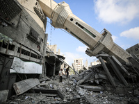 Palestinians are standing on the rubble of Abdullah Azzam Mosque, destroyed in Israeli bombardment in Nuseirat, central Gaza Strip, on July...