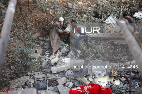 Palestinians are inspecting a house destroyed in an Israeli strike, amid the Israel-Hamas conflict, in Nusairat refugee camp, in the central...