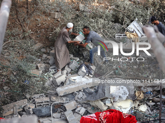 Palestinians are inspecting a house destroyed in an Israeli strike, amid the Israel-Hamas conflict, in Nusairat refugee camp, in the central...