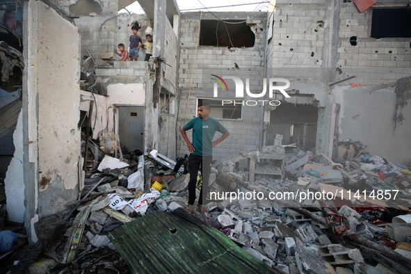 Palestinians are inspecting a house destroyed in an Israeli strike, amid the Israel-Hamas conflict, in Nusairat refugee camp, in the central...