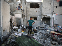 Palestinians are inspecting a house destroyed in an Israeli strike, amid the Israel-Hamas conflict, in Nusairat refugee camp, in the central...