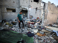 Palestinians are inspecting a house destroyed in an Israeli strike, amid the Israel-Hamas conflict, in Nusairat refugee camp, in the central...