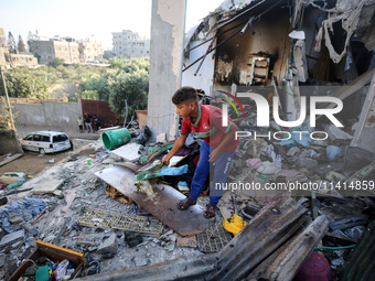 Palestinians are inspecting a house destroyed in an Israeli strike, amid the Israel-Hamas conflict, in Nusairat refugee camp, in the central...