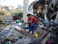 Palestinians are inspecting a house destroyed in an Israeli strike, amid the Israel-Hamas conflict, in Nusairat refugee camp, in the central...