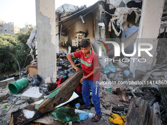 Palestinians are inspecting a house destroyed in an Israeli strike, amid the Israel-Hamas conflict, in Nusairat refugee camp, in the central...