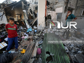 Palestinians are inspecting a house destroyed in an Israeli strike, amid the Israel-Hamas conflict, in Nusairat refugee camp, in the central...