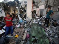 Palestinians are inspecting a house destroyed in an Israeli strike, amid the Israel-Hamas conflict, in Nusairat refugee camp, in the central...