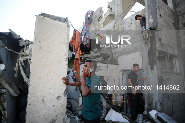 Palestinians are inspecting a house destroyed in an Israeli strike, amid the Israel-Hamas conflict, in Nusairat refugee camp, in the central...