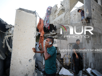 Palestinians are inspecting a house destroyed in an Israeli strike, amid the Israel-Hamas conflict, in Nusairat refugee camp, in the central...