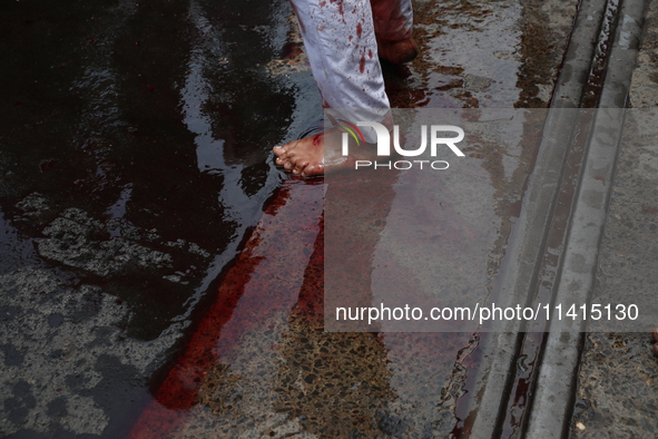 A Shi'ite Muslim is standing on a road after flagellating himself during a Muharram procession marking Ashura, in Kolkata, India, on July 17...