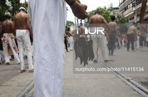 A Shi'ite Muslim is holding knives tied with a chain for flagellating himself during a Muharram procession marking Ashura, in Kolkata, India...