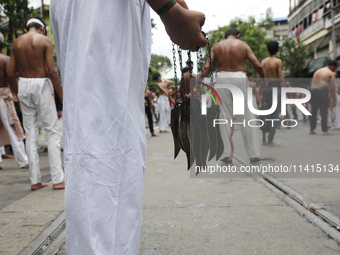 A Shi'ite Muslim is holding knives tied with a chain for flagellating himself during a Muharram procession marking Ashura, in Kolkata, India...