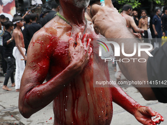 A volunteer is sprinkling rose water on the wounds of a Shi'ite Muslim after he flagellates himself during a Muharram procession marking Ash...