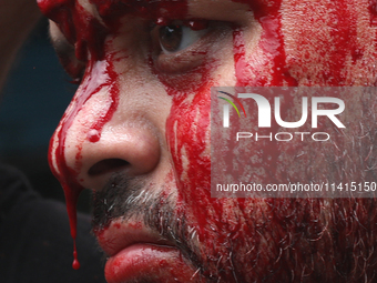 Blood is dripping from the nose of a Shi'ite Muslim man after flagellating himself during a Muharram procession marking Ashura, in Kolkata,...