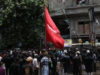 A Shi'ite Muslim is holding a religious flag during a Muharram procession marking Ashura, in Kolkata, India, on July 17, 2024. (