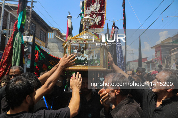 Kashmiri Shiite Muslim mourners are touching a glass case containing a copy of the Koran during a religious procession on the tenth day of A...