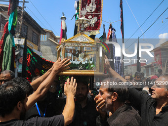 Kashmiri Shiite Muslim mourners are touching a glass case containing a copy of the Koran during a religious procession on the tenth day of A...