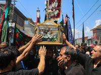 Kashmiri Shiite Muslim mourners are touching a glass case containing a copy of the Koran during a religious procession on the tenth day of A...