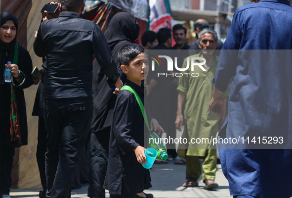 A Kashmiri Shiite Muslim boy is distributing water during a religious procession on the tenth day of Ashura in the Islamic month of Muharram...