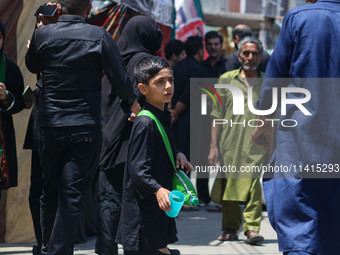 A Kashmiri Shiite Muslim boy is distributing water during a religious procession on the tenth day of Ashura in the Islamic month of Muharram...