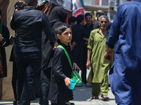 A Kashmiri Shiite Muslim boy is distributing water during a religious procession on the tenth day of Ashura in the Islamic month of Muharram...