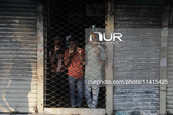 Street vendors are taking shelter inside a market as violence is erupting between police and anti-quota protestors in Dhaka, Bangladesh, on...