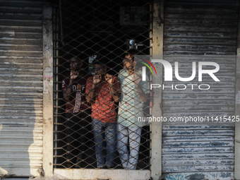 Street vendors are taking shelter inside a market as violence is erupting between police and anti-quota protestors in Dhaka, Bangladesh, on...