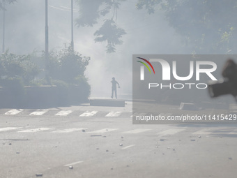 An anti-quota protestor is standing amidst the smoke of tear gas in Dhaka, Bangladesh, on July 17, 2024. (