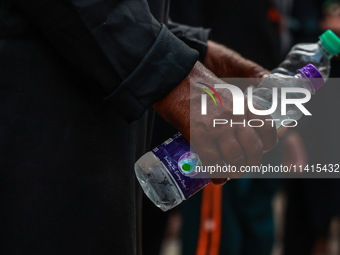 Shiite Muslims are keeping water bottles as they take part in the Ashura Procession on a hot day in Sopore, Jammu and Kashmir, India, on Jan...