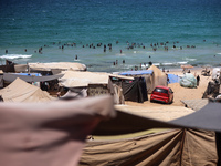 Displaced Palestinians are swimming next to a temporary camp in Deir el-Balah in the central Gaza Strip on July 17, 2024, amid the ongoing c...