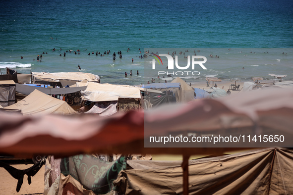 Displaced Palestinians are swimming next to a temporary camp in Deir el-Balah in the central Gaza Strip on July 17, 2024, amid the ongoing c...