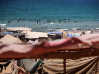 Displaced Palestinians are swimming next to a temporary camp in Deir el-Balah in the central Gaza Strip on July 17, 2024, amid the ongoing c...