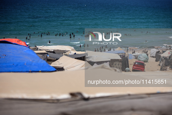 Displaced Palestinians are swimming next to a temporary camp in Deir el-Balah in the central Gaza Strip on July 17, 2024, amid the ongoing c...