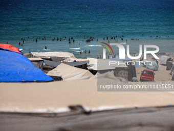 Displaced Palestinians are swimming next to a temporary camp in Deir el-Balah in the central Gaza Strip on July 17, 2024, amid the ongoing c...