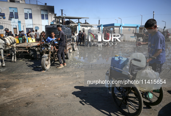 Palestinians are filling containers with water at a desalination plant in Deir el-Balah in the central Gaza Strip on July 17, 2024, amid the...